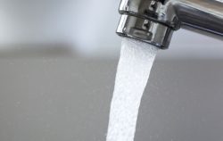 A close up view of a tap with water coming out.
